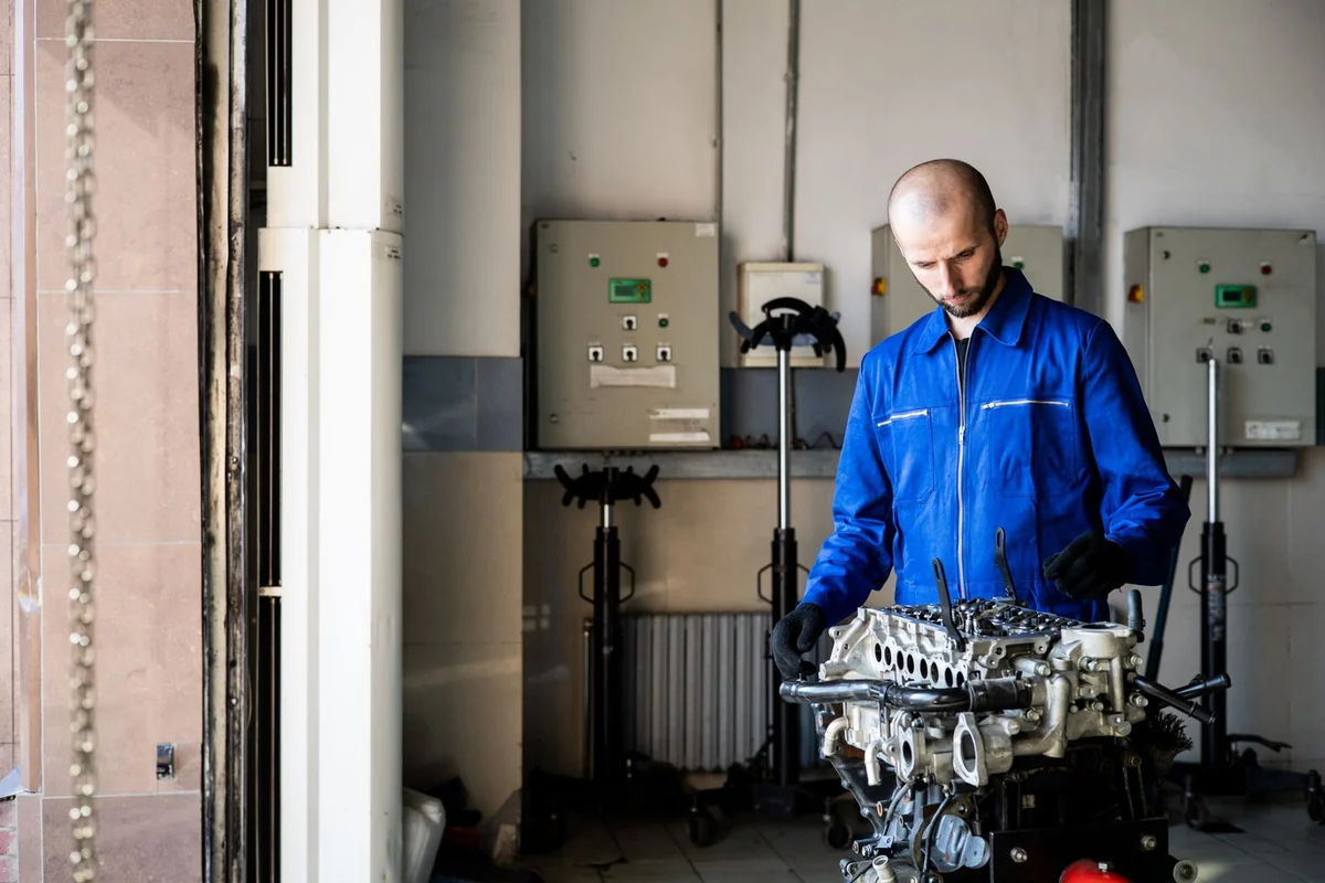 Techniker arbeitet in einer Werkstatt an einem aufgebockten Motor