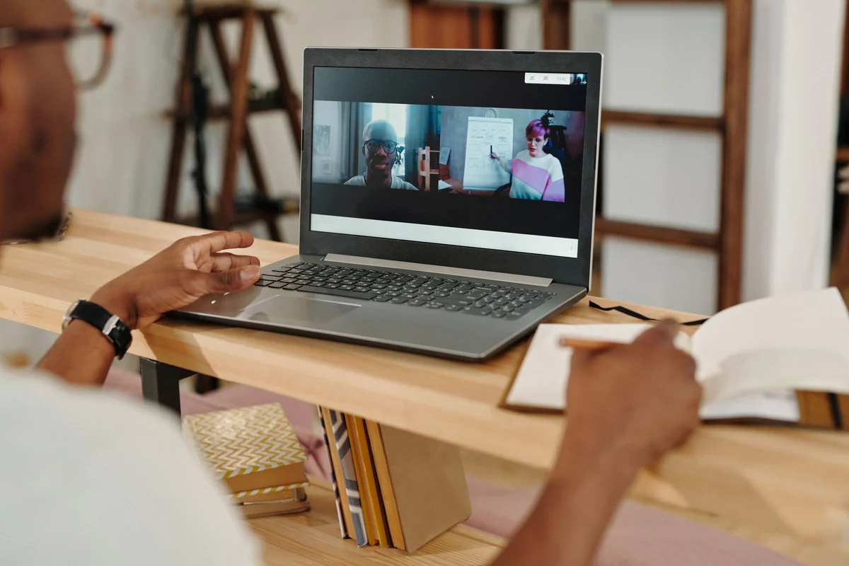 Person verfolgt am Laptop ein Online-Seminar und macht sich Notizen