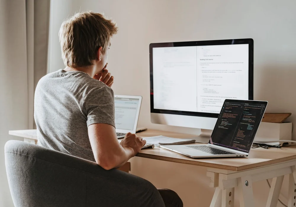 Entwicklerarbeitsplatz mit Quellcode auf mehreren Monitoren