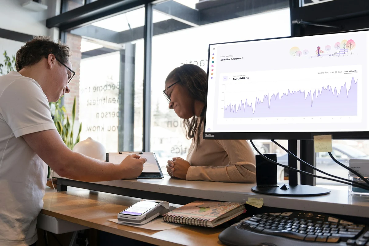 Zwei Personen besprechen eine Auswertung auf einem großen Monitor