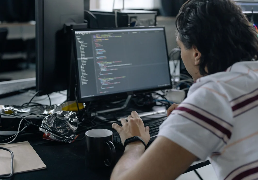 Entwickler am Monitor mit geöffnetem Code-Editor